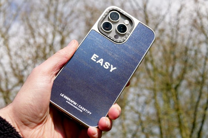 A person holding an iPhone 15 Pro Max with a Casetify x Le Sserafim case.
