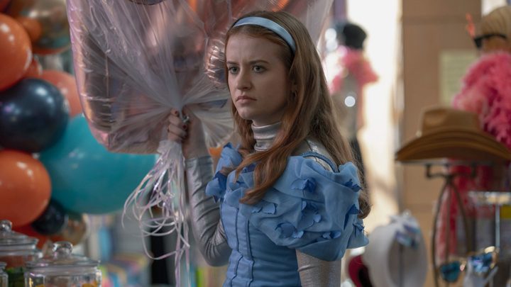A young woman dressed up for a party holding balloons in a scene from Extraordinary on Hulu.