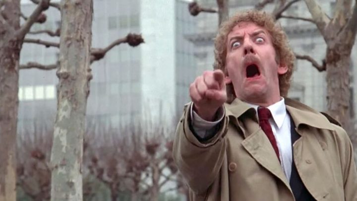 A young Donald Sutherland, mouth agape pointing a finger in a scene from Invasion of the Body Snatchers.