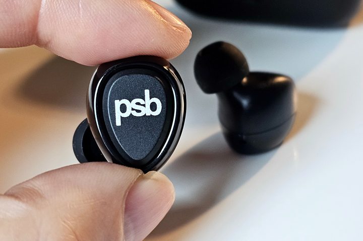 PSB Speakers M4U TWM left earbud held between a finger and a thumb.