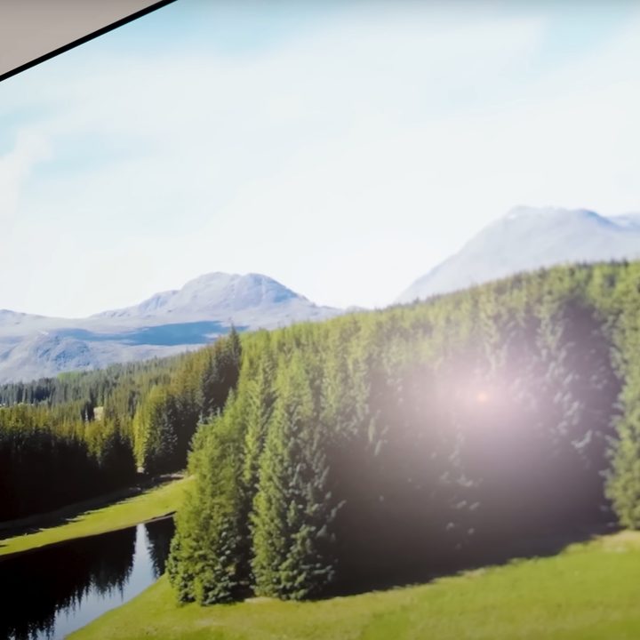 A glare from lights is seen on Samsung S95D OLED TV displaying a natural vista.