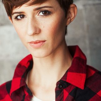 A headshot of Sarah Elmaleh shows her wearing a red shirt.
