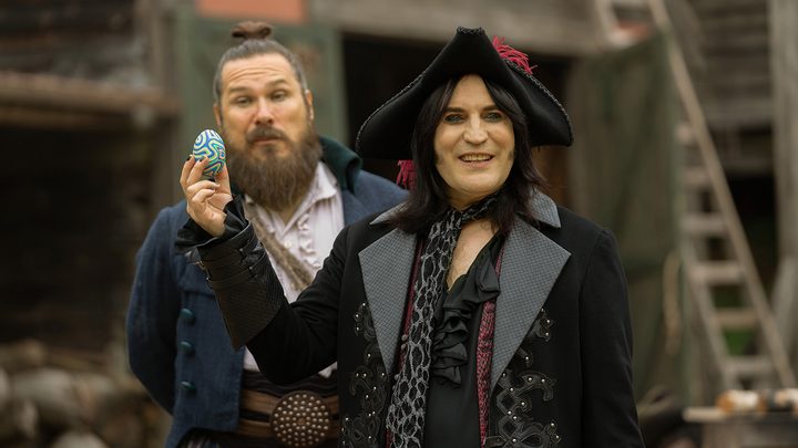 Two men wearing historical costumes, one holding up a designer egg in a scene from The Completely Made-Up Adventures of Dick Turpin on Apple TV+.