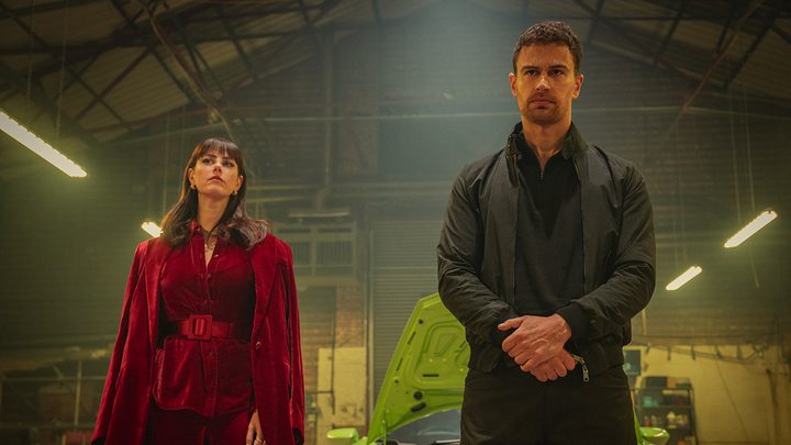 A woman and man stand in a warehouse in a scene from The Gentlemen on Netflix.