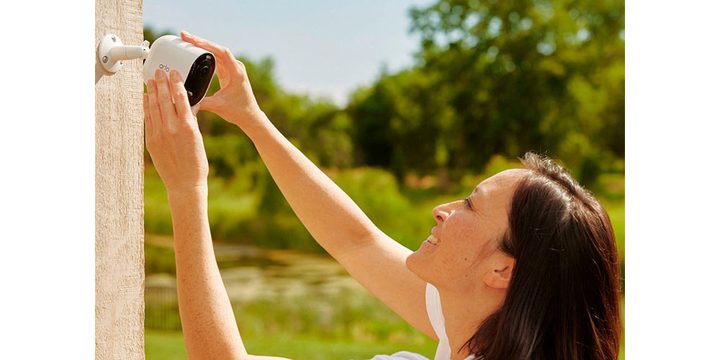 A woman assembling a Arlo Pro 5S on a wall.