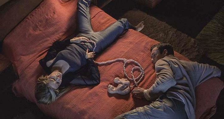 Two people lie on a bed in eXistenZ.