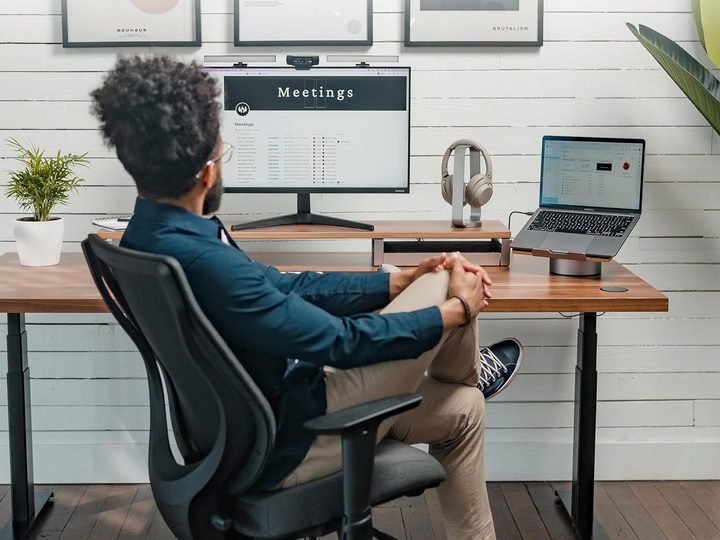 A man uses the HumanCentric Laptop Stand alongside his work from home monitor.