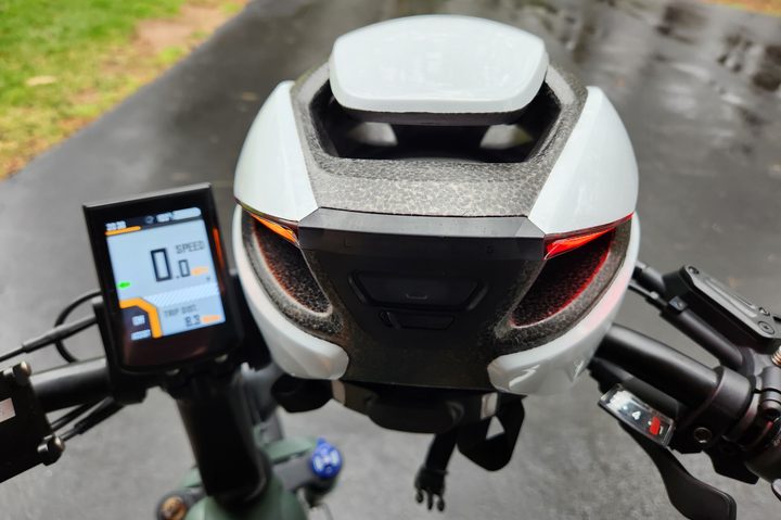 Lumos Ultra lighted helmet resting on MOD Easy 3 Sidecar handlebars with left signal light orange and left turn indicator on the e-bike display.