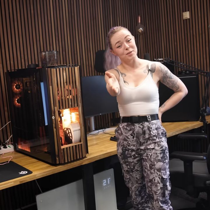 A woman stands next to a custom-built gaming PC with a coffee maker inside.