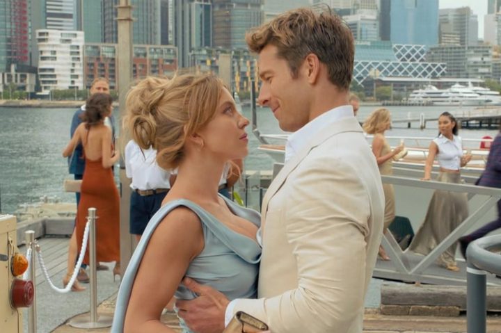 A man holds a woman as they stare into each other's eyes.