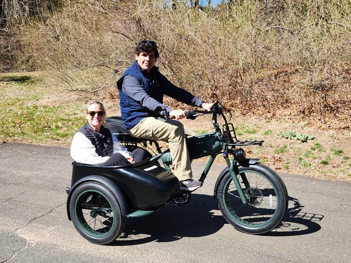 Two peoplle on a MOD Easy Sidecar 3 on a private road with trees in the background