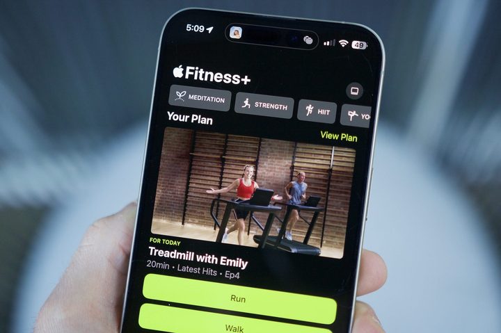 Someone holding an iPhone with the Apple Fitness app open, showing the Custom Plans feature.