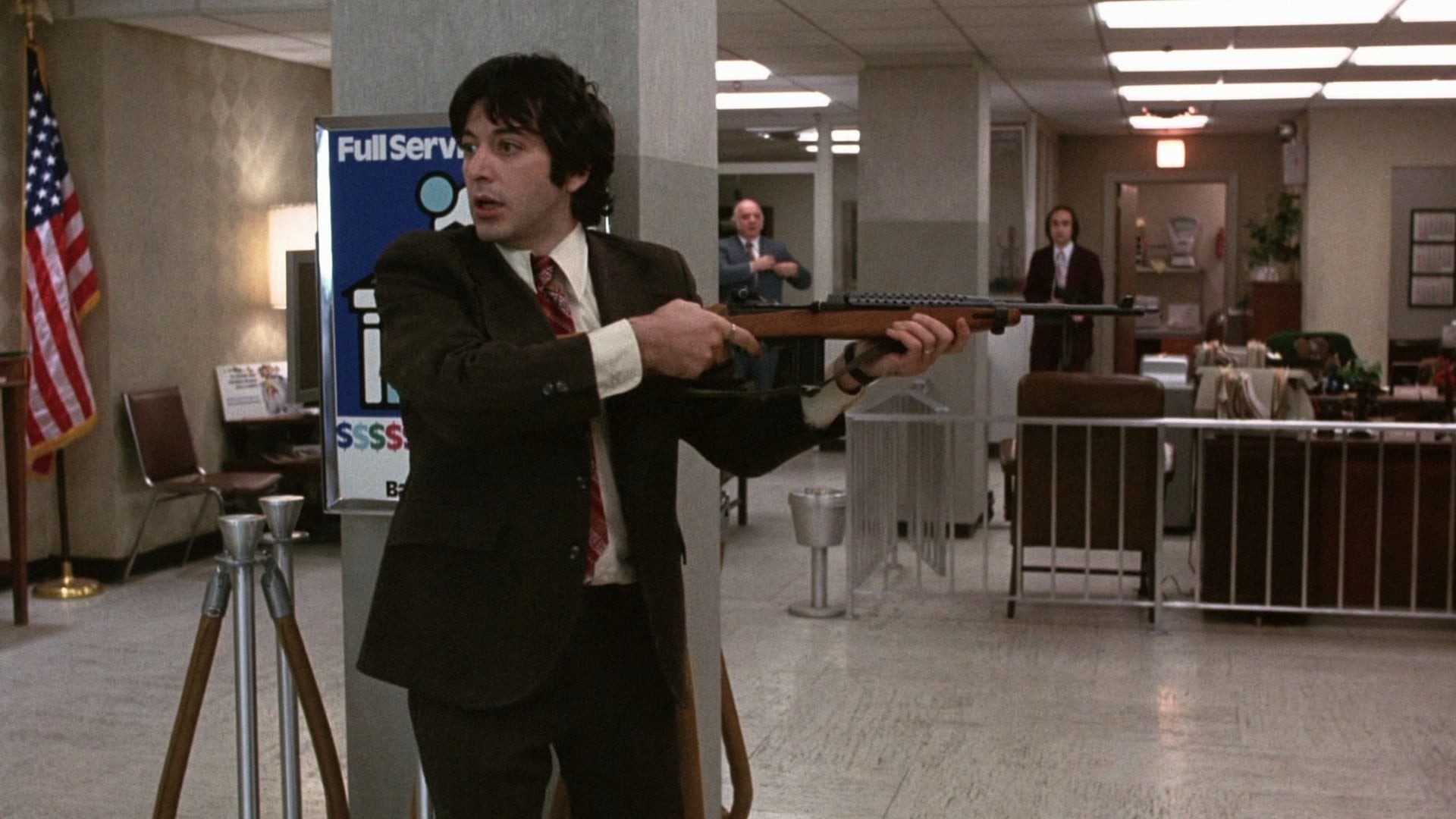 Al Pacino holding a gun while robbing a bank in Dog Day Afternoon.