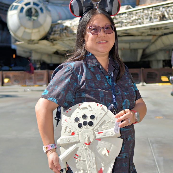 Person holding Millennium Falcon in front of the Millennium Falcon.