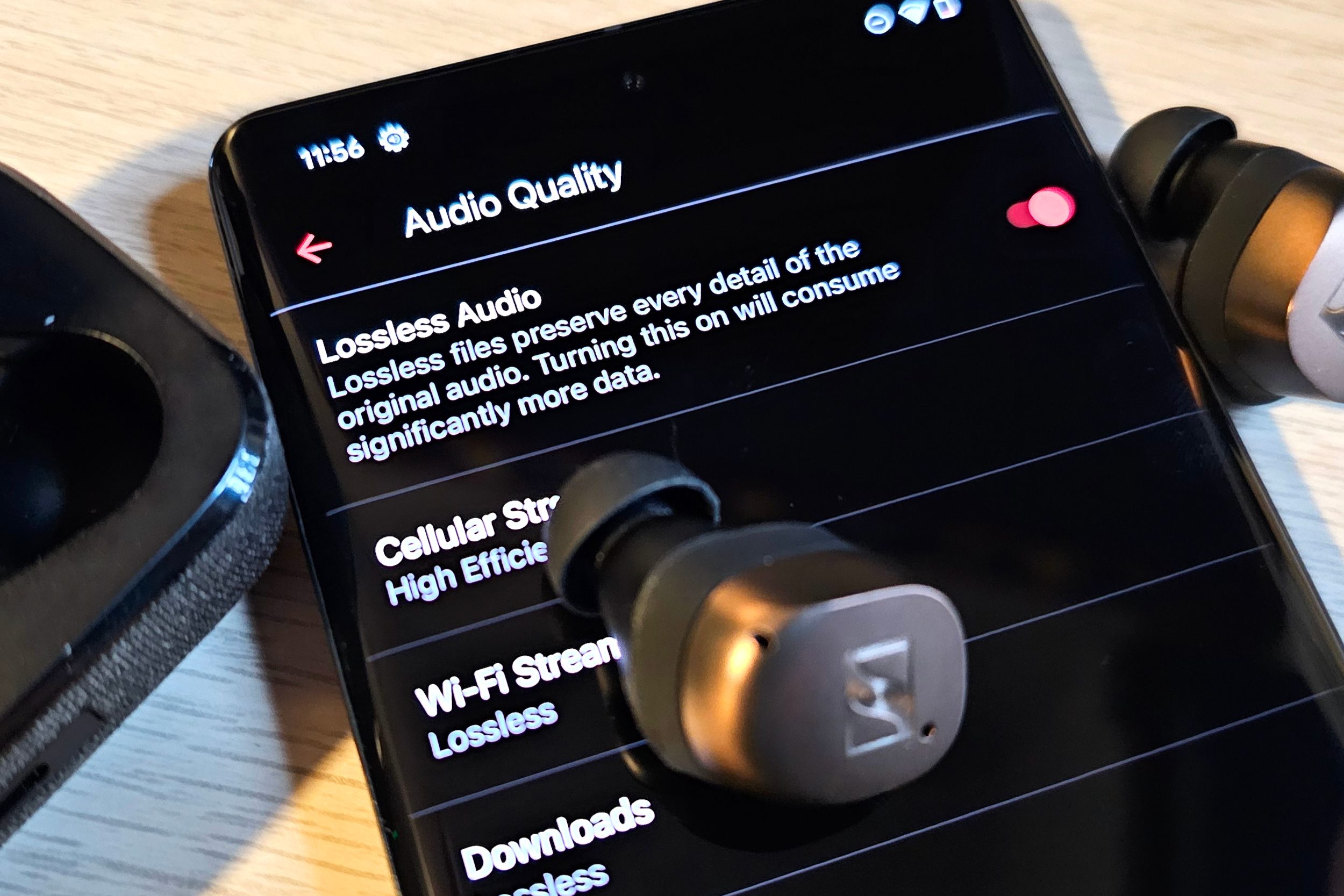 A Google Pixel 7 Pro displaying Apple Music's lossless audio, next to a pair of Sennheiser Momentum True Wireless 4 earbuds.