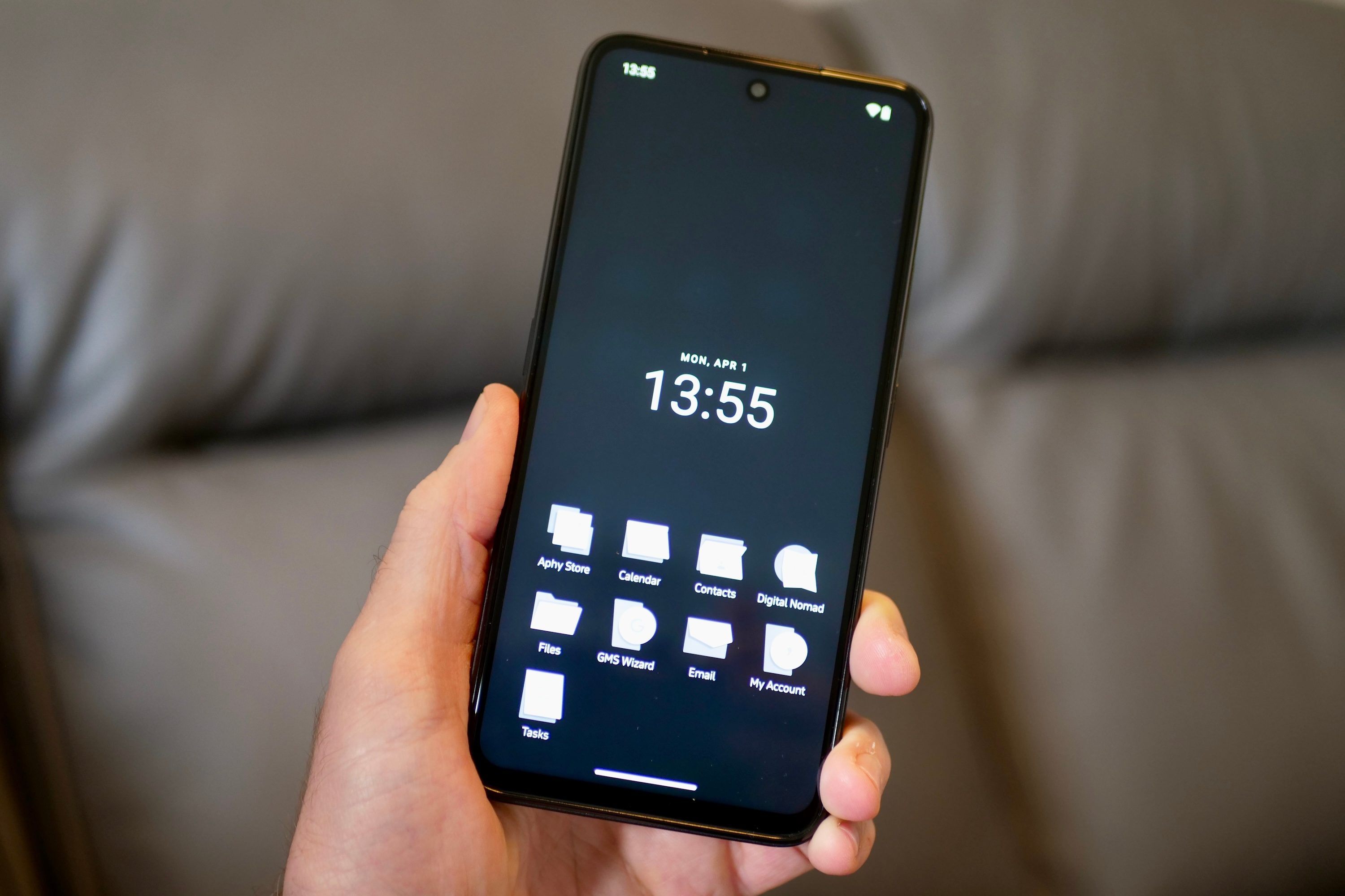 A person holding the Punkt MC02, showing the black homescreen with private apps.