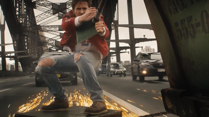 A man holds on to a speeding car in The Fall Guy.
