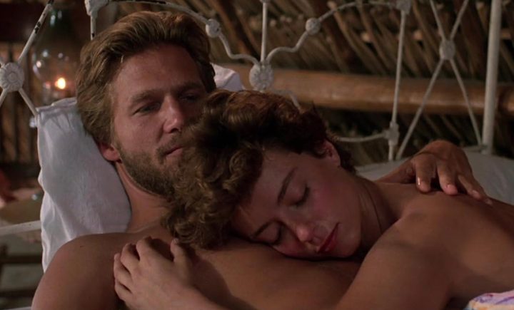 A man lies down as a woman rests her head on his chest.