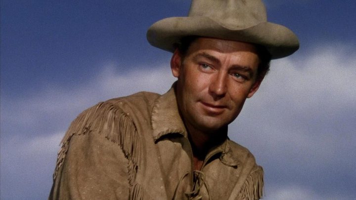 Alan Ladd as Shane smiling and looking off-camera in Shane.