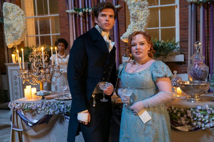 A boy and girl stand next to each other while holding drinks.