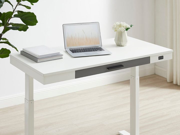 The Insignia adjustable powered 1-drawer standing desk with a laptop o top.