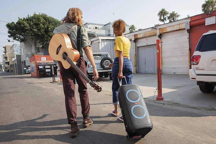 Two people walking along a street dragging the JBL PartyBox 310 behind them.