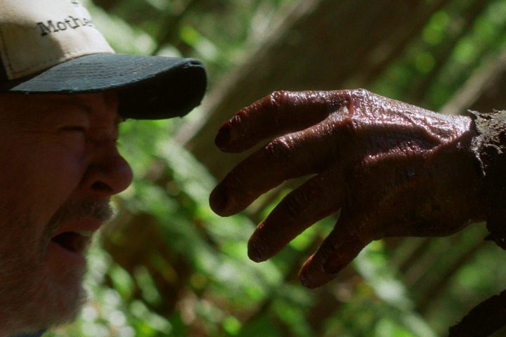 Johnny's hand reaches toward a terrified man in In a Violent Nature.