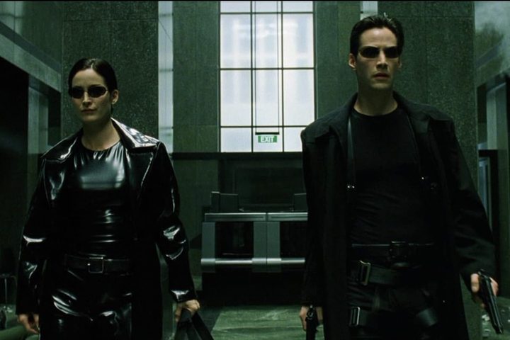A woman and man stand next to each other while holding guns.