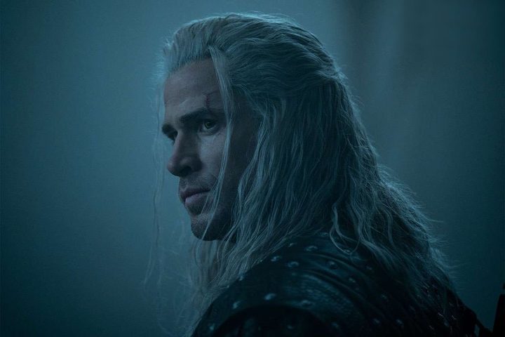 Liam Hemsworth looks and stares over hid shoulder.