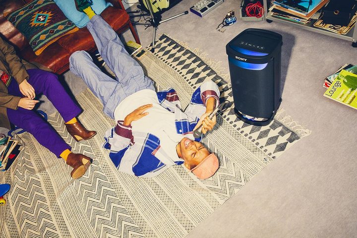 A man lying on the floor next to the Sony SRS-XP500.
