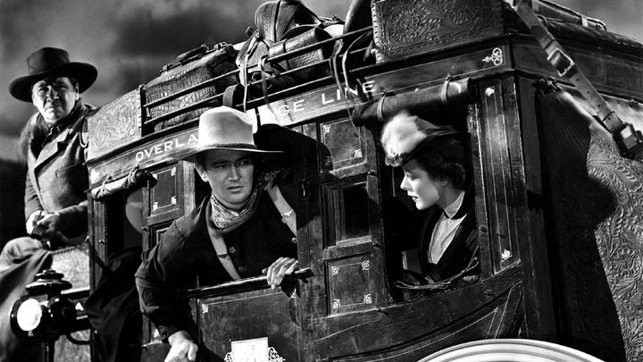 Three people sticking their heads out of a train in the film Stagecoach.