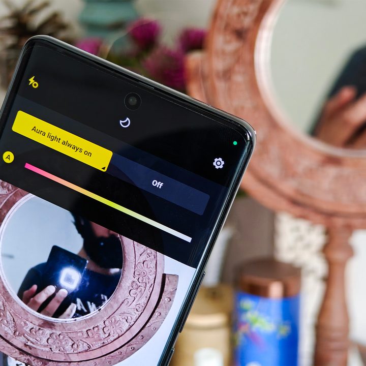 Aura Light on a gray Vivo V30 Pro held by a man in the hand against a circular mirror.