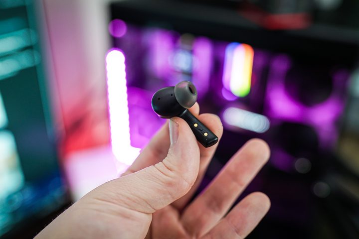 A hand holding the left side of the Asus Cetra Speednova earbuds.