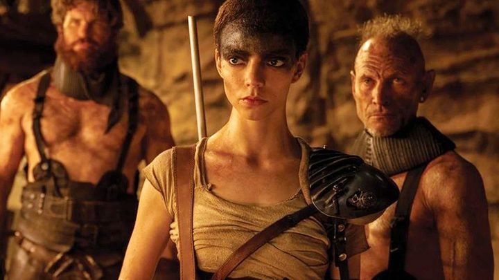Furiosa and two men stand in Furiosa: A Mad Max Saga.