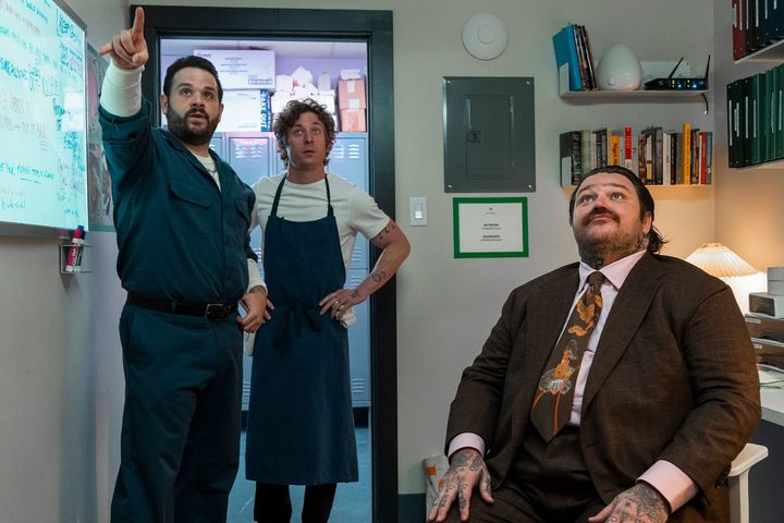 Three men stand and sit in an office in The Bear season 3.