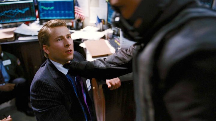 Bane grabs a man by the neck in The Dark Knight Rises.