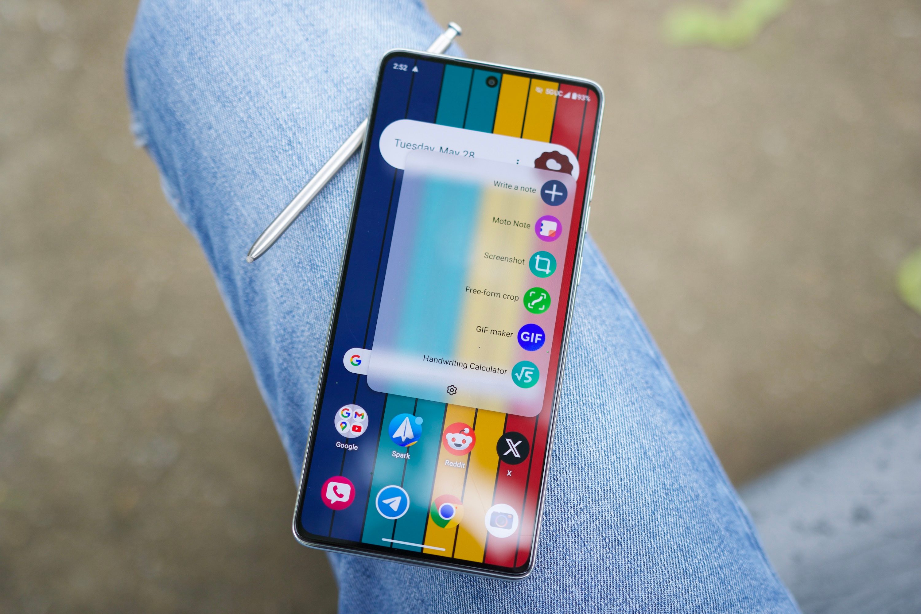 The Moto G Stylus 5G (2024) resting on someone's leg, with the stylus laying behind it.