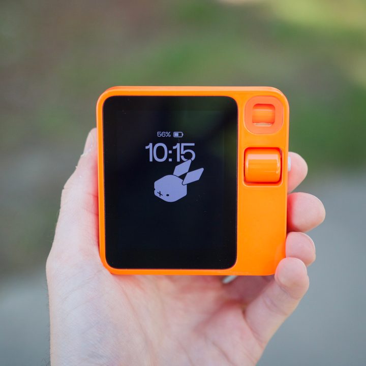 Someone holding the Rabbit R1 outside.