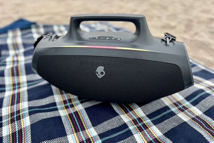 The Skullcandy Barrel Bluetooth speaker on a plaid beach blanket.