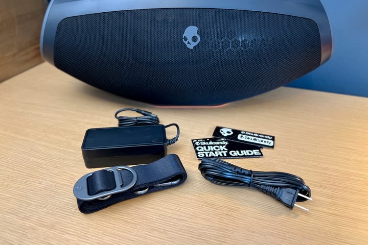 The Skullcandy Barrel Bluetooth speaker with its strap and AC adapter.