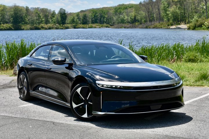 Front three quarter view of a black 2024 Lucid Air Pure in front of a lake.