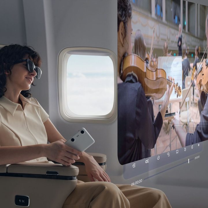 A person on a plane watches a giant virtual screen with Xreal Air 2 and Beam Pro.