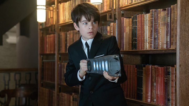 Artemis Fowl aiming a gun at something off-camera in Artemis Fowl.