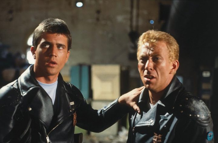 Mel Gibson puts his hands on someone else's shoulder.