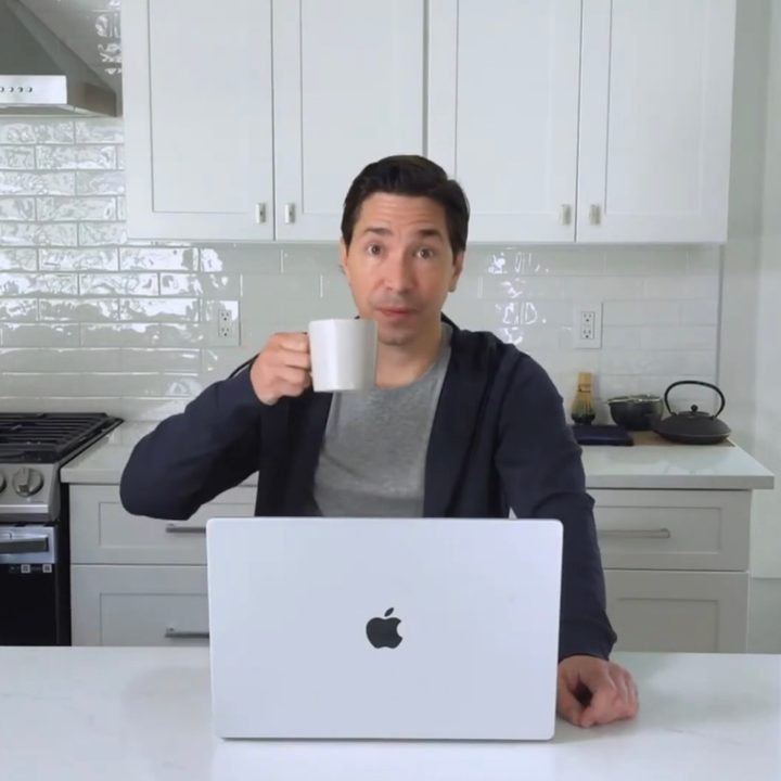 Justin Long sits with a MacBook and drinks tea.