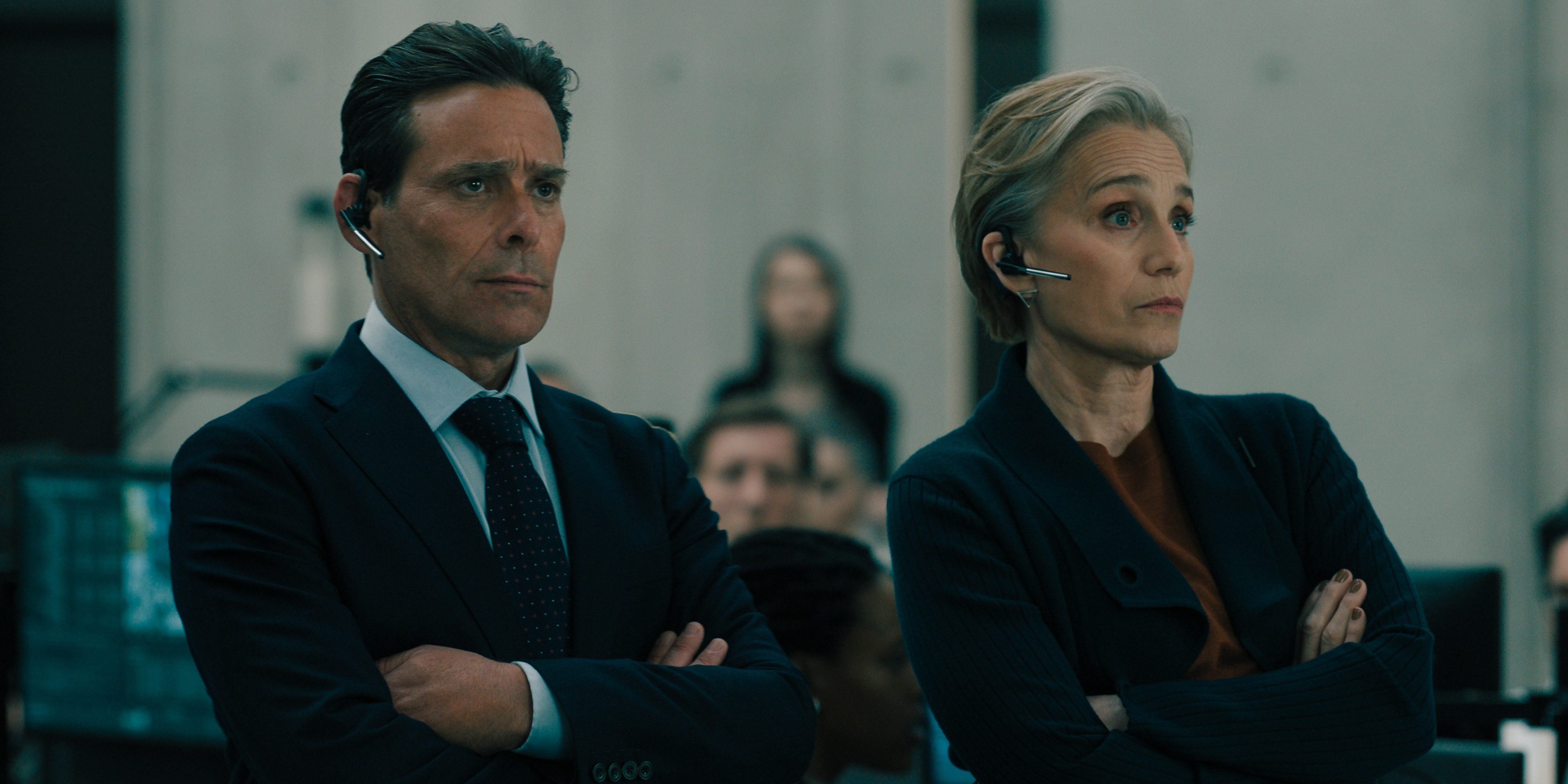 A man and woman stand next to each other with arms under armpits.