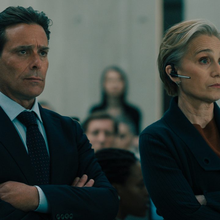 A man and woman stand next to each other with arms under armpits.