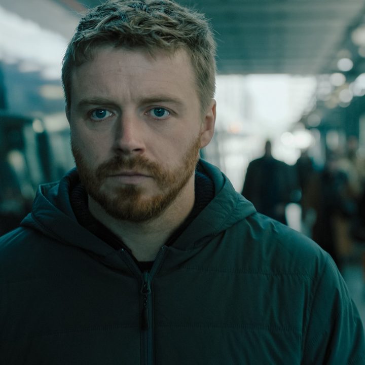 A bearded man stares at someone.