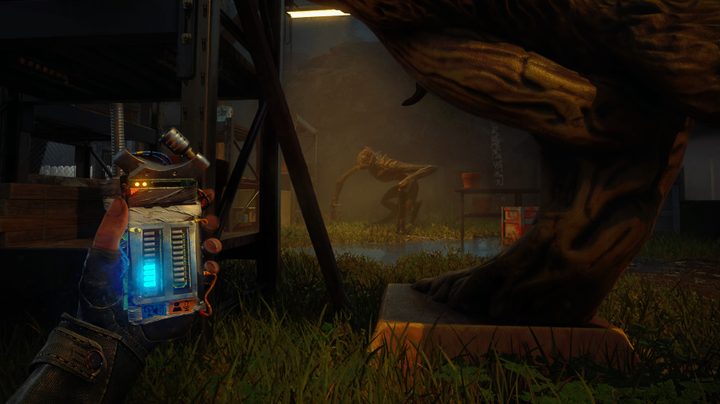 The player character in first person holding a detector while hiding from a Quiet Place alien.