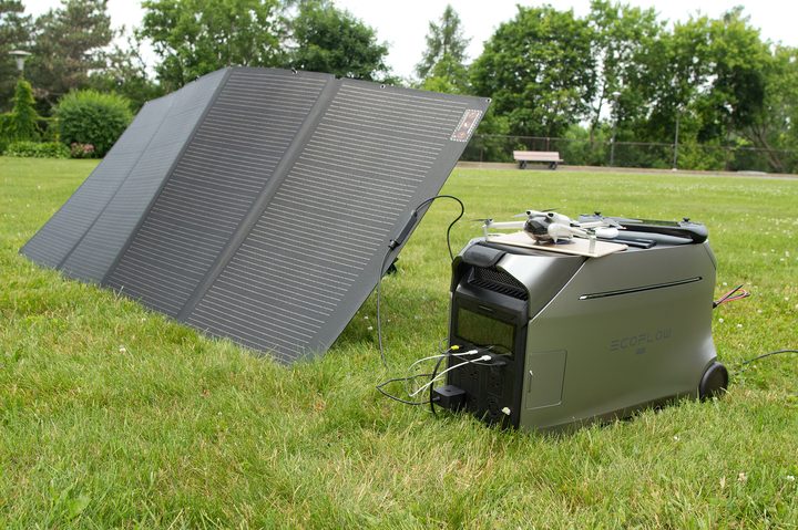 EcoFlow Delta Pro 3 power station on grass, connected to solar panels and several personal devices.